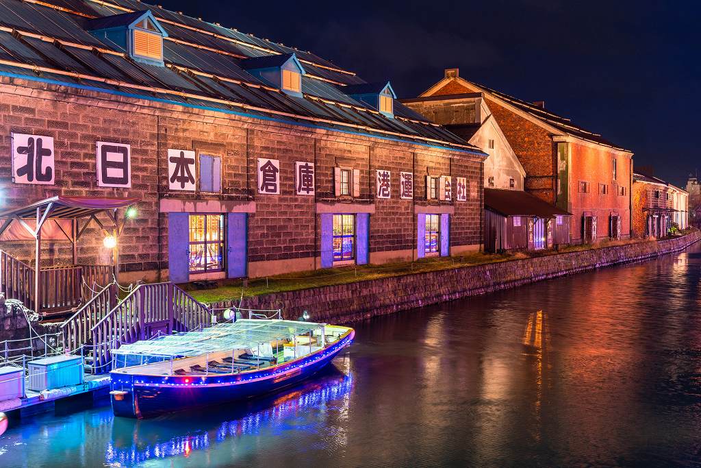 倉庫内から暖かな光が漏れ、水面が彩られる日暮れの小樽運河