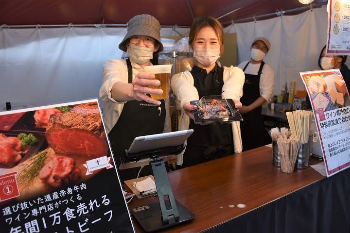 料理とビールを勧めるフェアのスタッフ