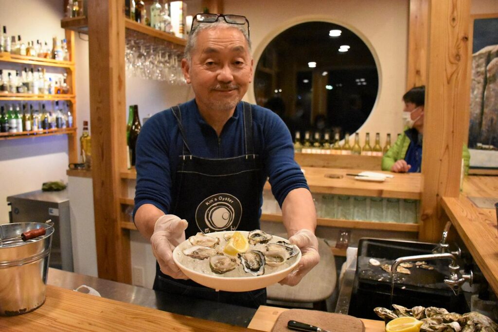 オイスターバー「牡蠣場（かきば）」の店内で剥いたカキを提供してくれる中嶋さん