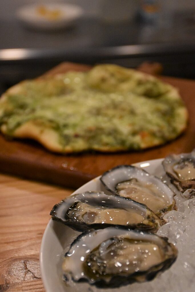 皿に並べられた「カキえもん」と、後方にはピザ