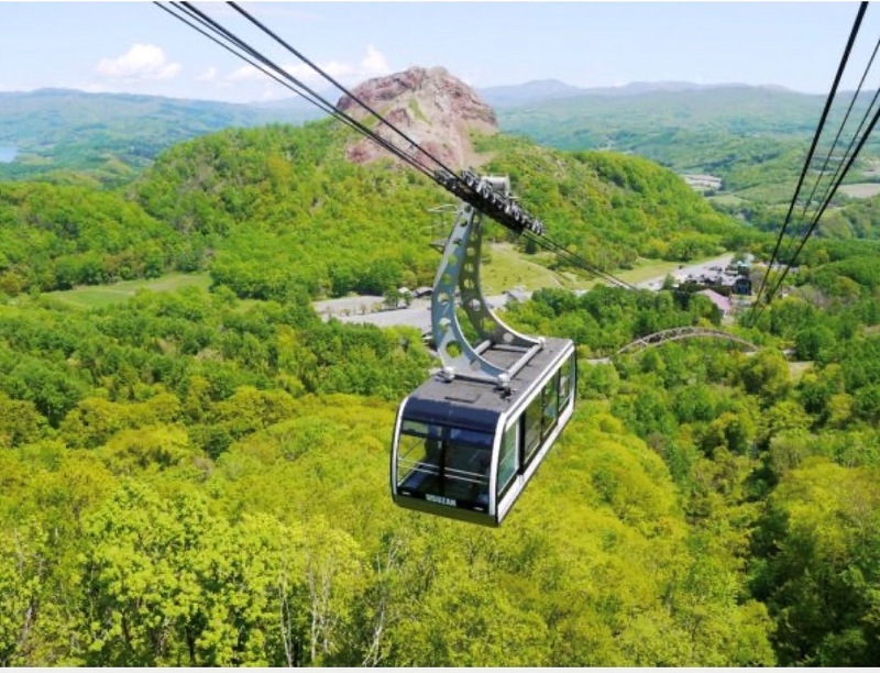 昭和新山をバックに山頂に向かうロープウェイのゴンドラ