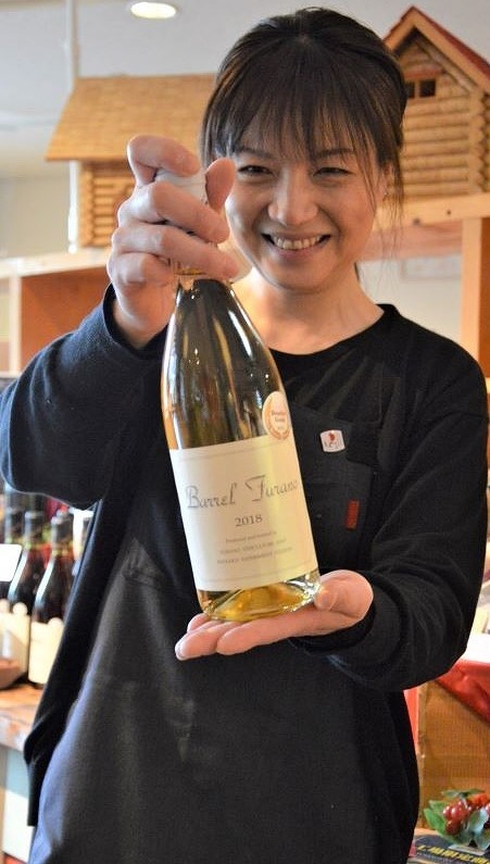 富良野市ぶどう果樹研究所の「バレルふらの(白)2018」を持つ関係者の女性