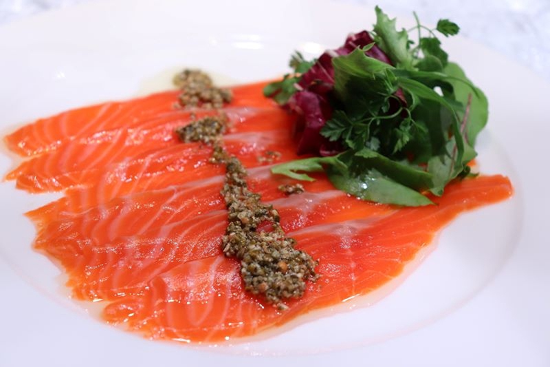 ディナータイムで提供されている「北海道二海サーモンのマリネ　グリーンペッパー風味　丘珠産水耕栽培　新芽野菜添え」