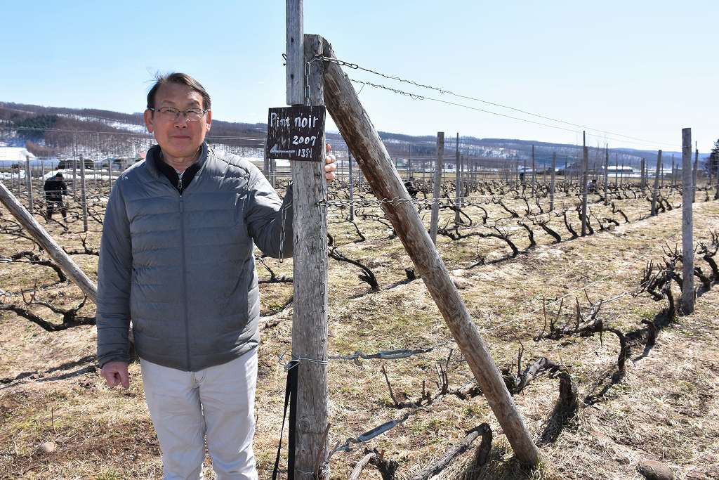 ワイン畑の前で「この子たちには迷惑をかけてます」と話す多田繁夫さん