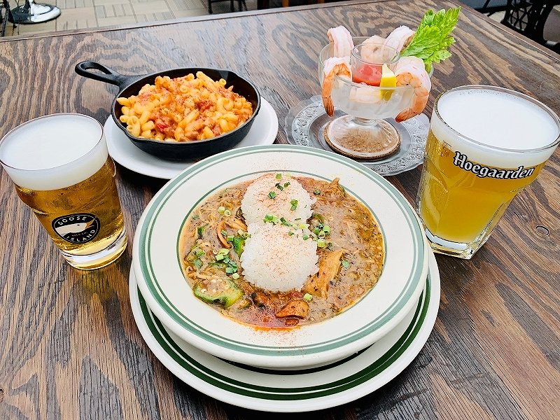 BUDDYBUDDYで提供しているニューオリンズの名物料理「ガンボ」（手前中央）とビールの「グースIPA樽生」（手前左）、「ヒューガルデンホワイト樽生」（手前右）