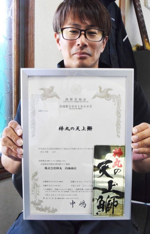 「棒丸の天上鰤」の商標登録証を手にする内海社長