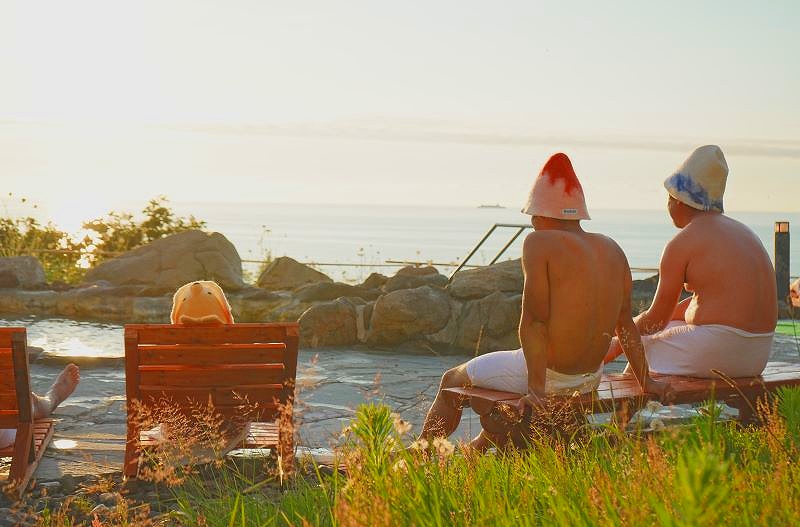 露天風呂のベンチで景色を楽しみながらクールダウンする笑顔の参加者