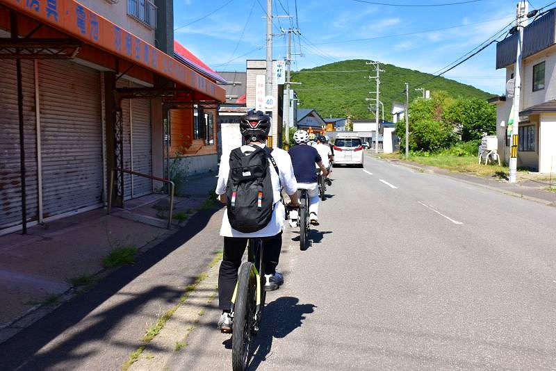 隊列を組んで「Ｅバイク」を走らせるツアー参加者