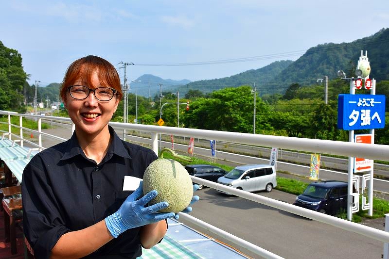 １玉の夕張メロンを手に「まさに今が夕張メロンが美味しい時期ですよ」と笑顔を見せる従業員