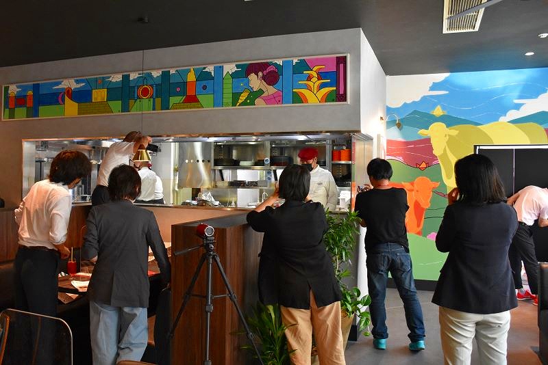 Tボーンステーキを焼くライブパフォーマンスの様子を撮影するマスコミ関係者