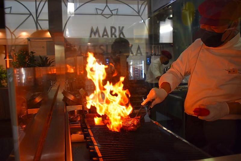 炎が立ち上げて焼き上げるＴボーンステーキの調理風景