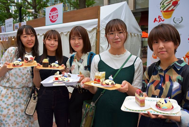 会場限定スイーツを購入して笑顔を見せる女性5人のグループ