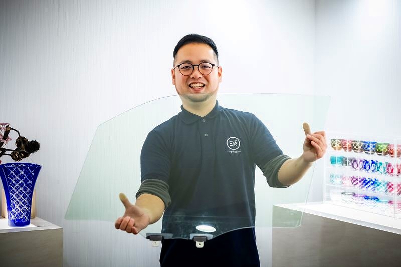 1枚1枚、手作業で外されて、深川硝子工芸に運ばれてくる原料の窓ガラスを手にする出口社長