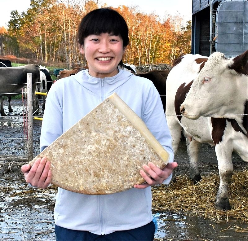 フィルムで包まれたチーズ「フロマージュド美瑛 夏ミルク」を手にする小熊さん