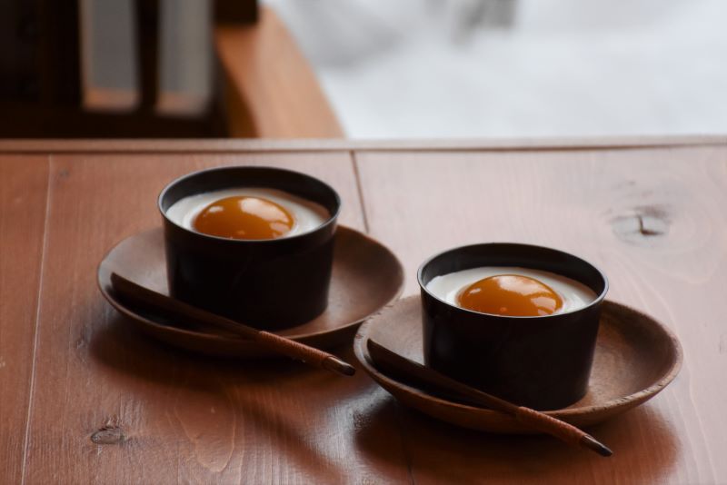 受け皿の上にスプーンが添えて提供された、目玉焼きのような見た目の「定山渓玉子ぷりん」2個