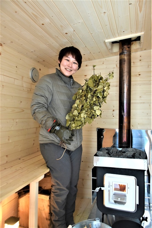 移動式の「どこでもサウナ」内で、シラカバの枝葉を束ねたヴィヒタを手にする谷山嘉奈美さん