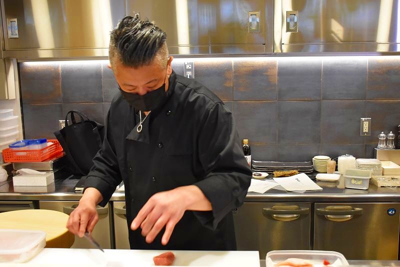 すしネタを包丁でさばく寿司「天金」の従業員