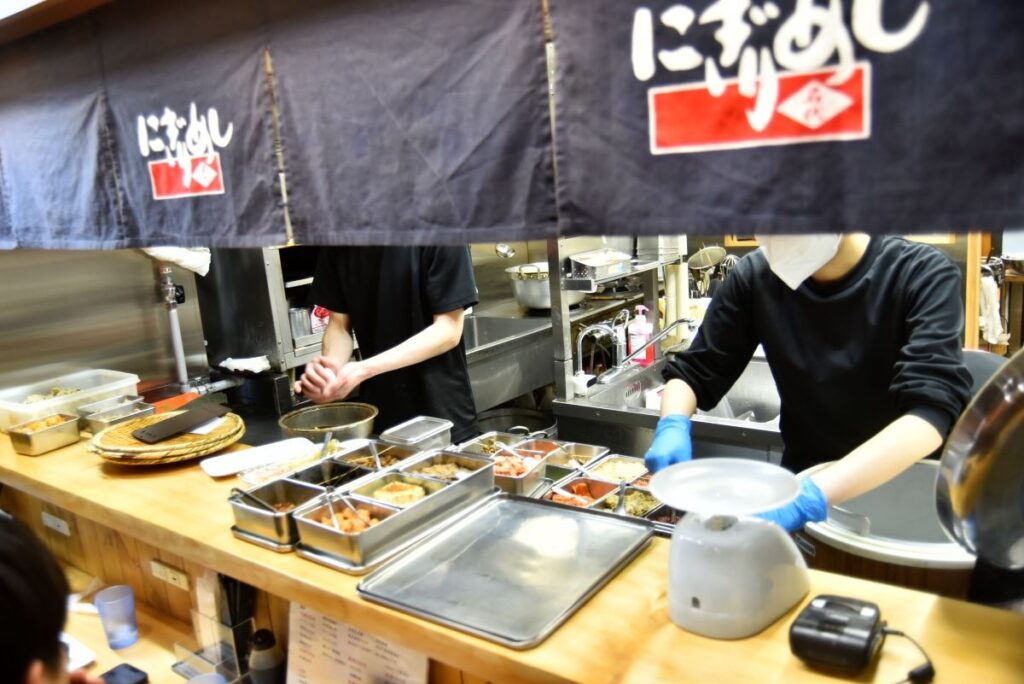 目の前には具材がずらりと並び、席から握る姿を見ることができる「名代にぎりめし」のカウンター席