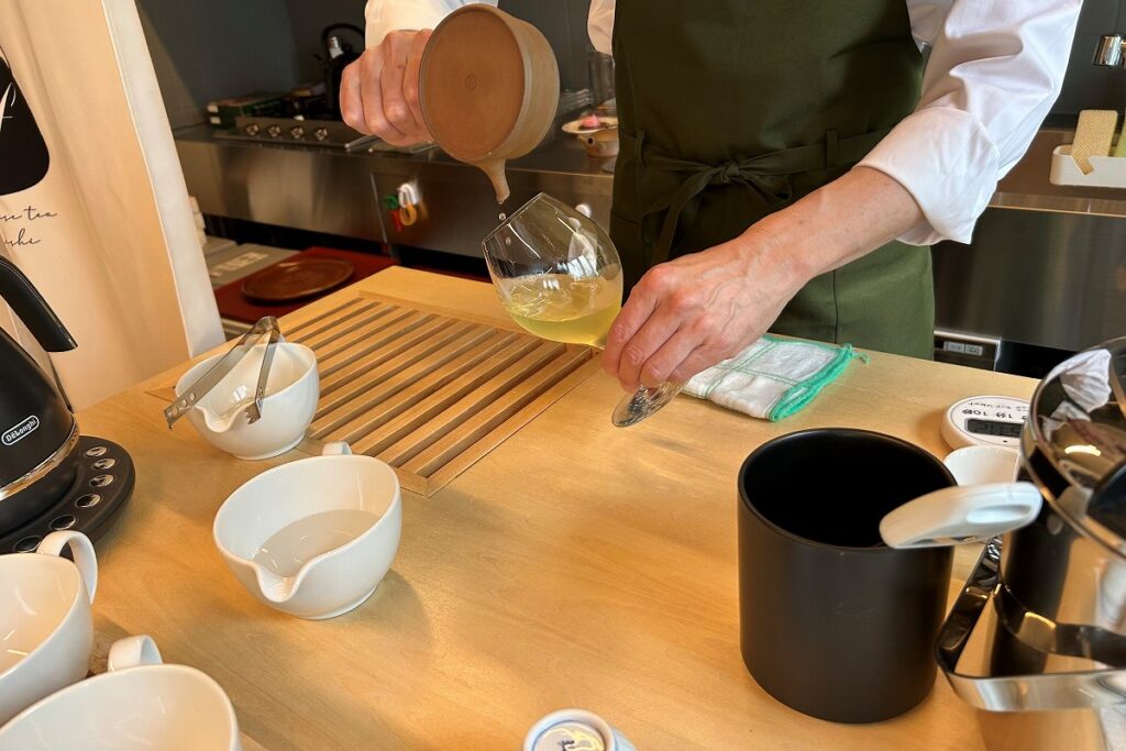 急須に氷を入れて抽出した冷たい煎茶をグラスに注いでいる様子