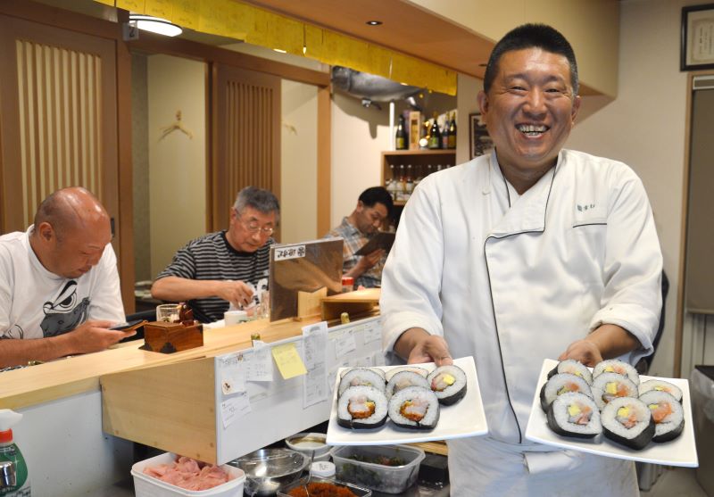 ビジネス客で埋まるカウンターですしや巻きものを振る舞う池田さん