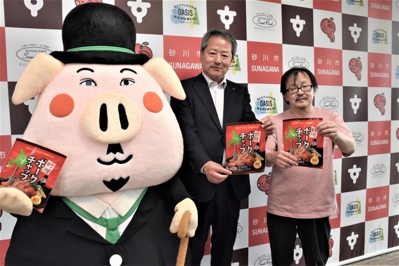 「砂川ポークチャップ」の冷凍食品をPRする(右から)砂川ポークチャップ協議会の重木均会長とソラチの桑原朗社長、イメージキャラクターの砂川・ポークチャップリン