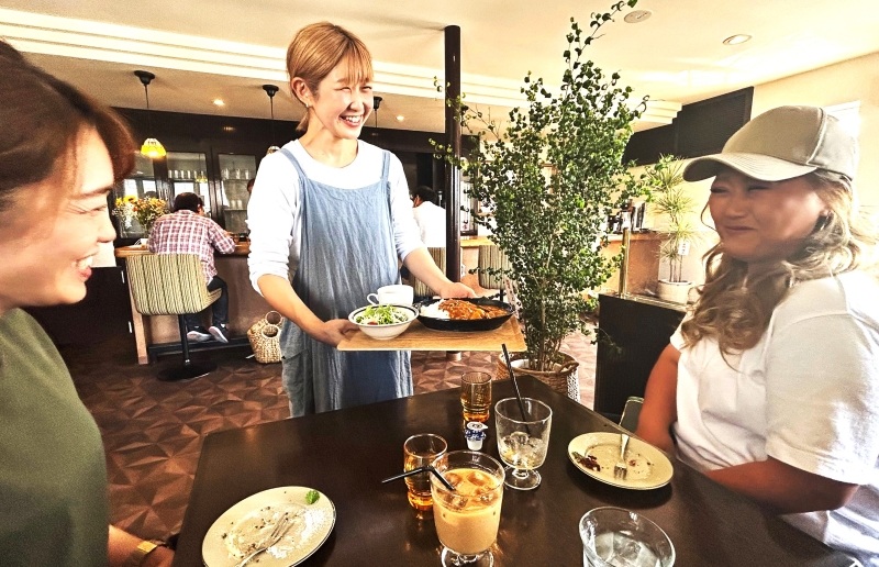 お祝いのため駆けつけた友人を前に笑顔で接客する村上さん（中央）