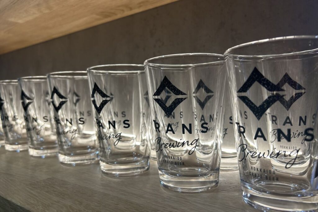 カウンターの向こうに並んだ、ロゴ入りのピカピカのグラス