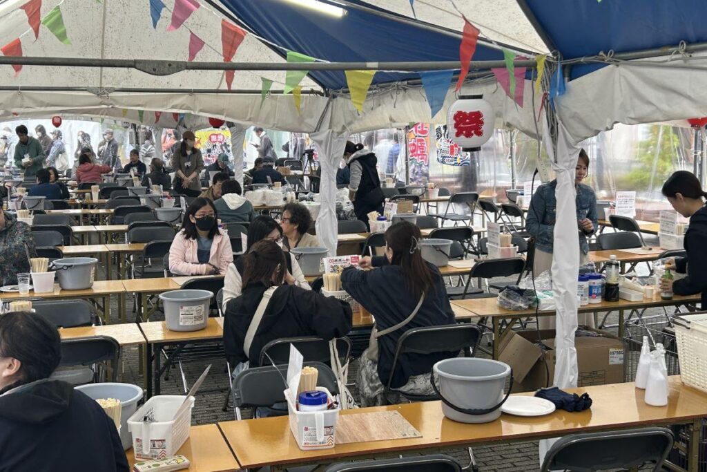 会場の飲食スペース。軍手や貝むきナイフ、殻を入れるバケツ、ウェットティッシュなどがテーブルに備え付けられている