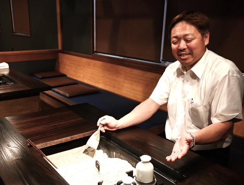 店内に設けた囲炉裏を前にする山田一男代表