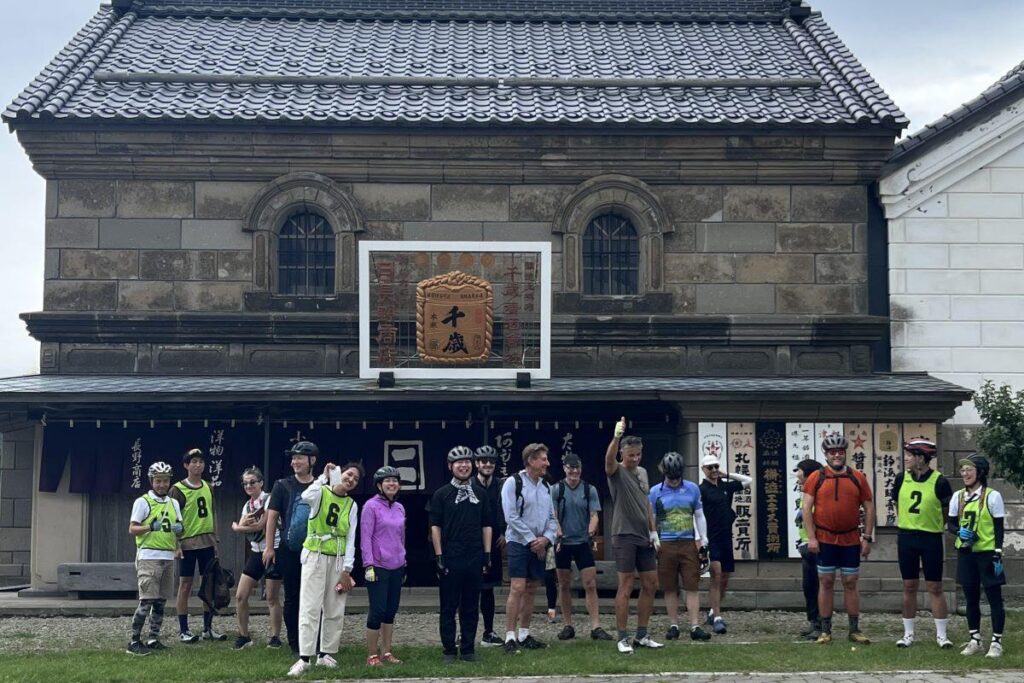 保存されている旧長野商店の前で記念撮影する参加者