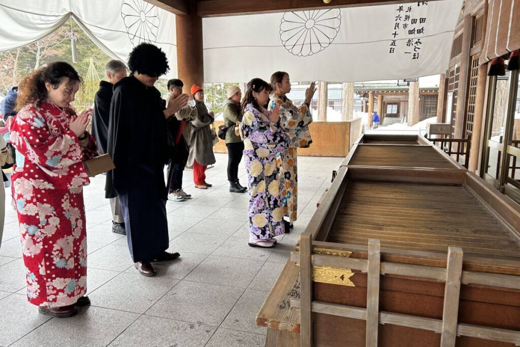 真剣に手を合わせてお祈りする参加者ら