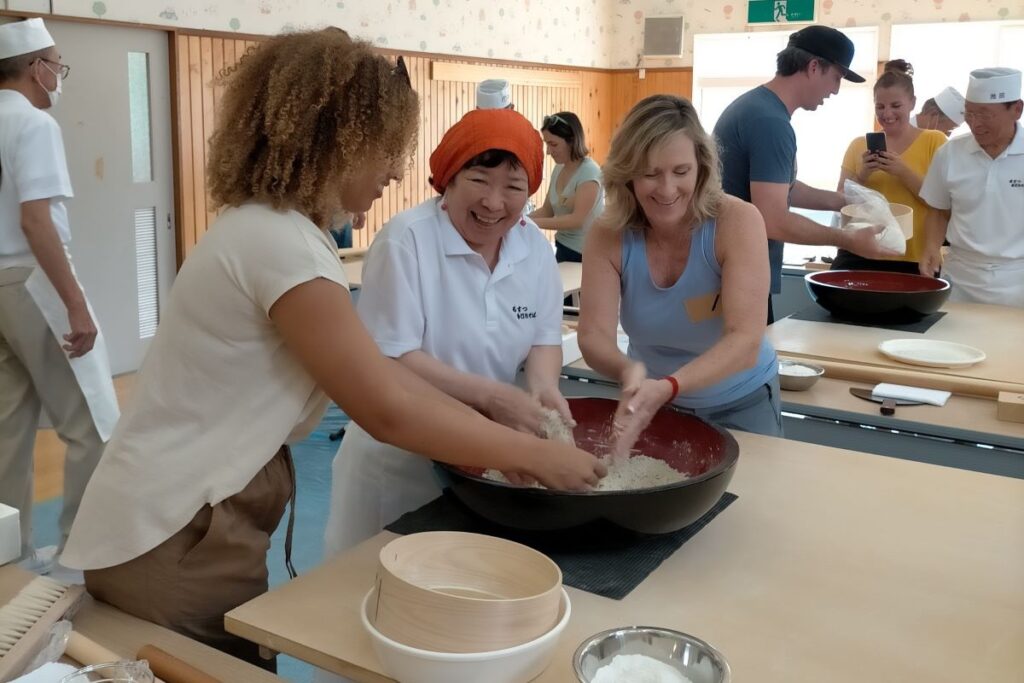 地元の人の指導でそば打ちを体験する参加者