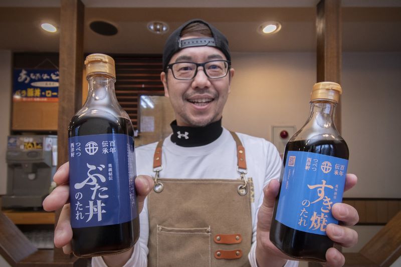 発売した「ぶた丼のたれ」(左)と「すき焼のたれ」を持つ榎本さん