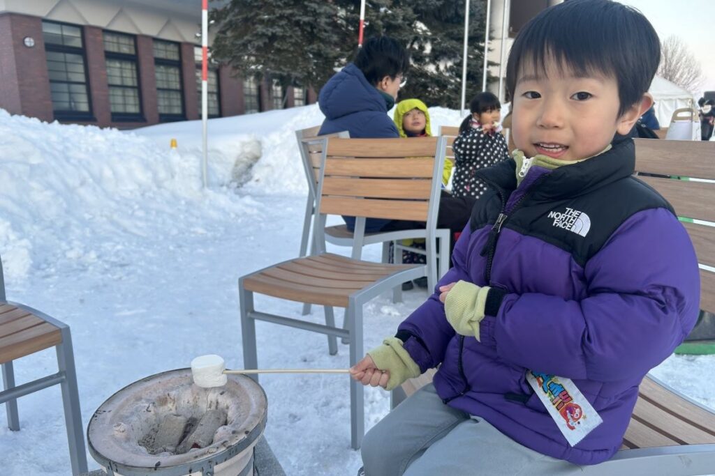 串に刺したマシュマロを七輪であぶる子ども