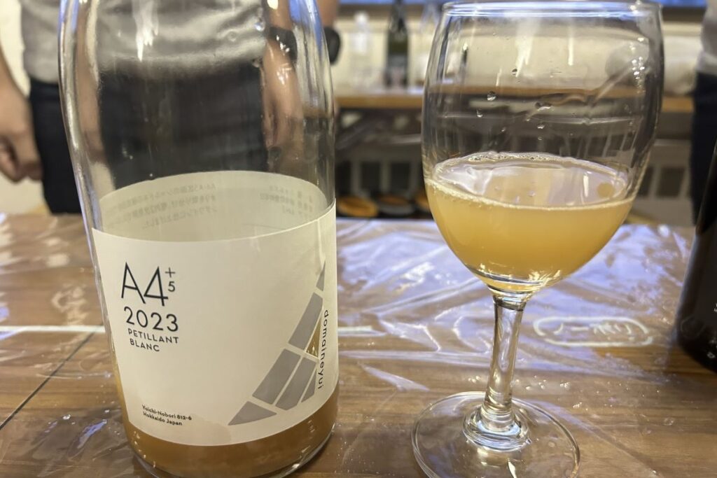ドメーヌユイのA4+5ペティアンブラン2023のボトルと注がれたグラス