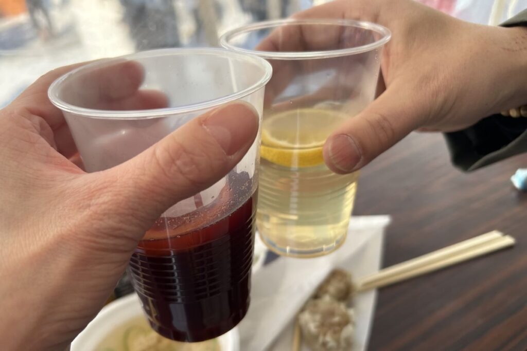 ホットワインサングリア(左)とブラックニッカのお湯割りで乾杯している様子