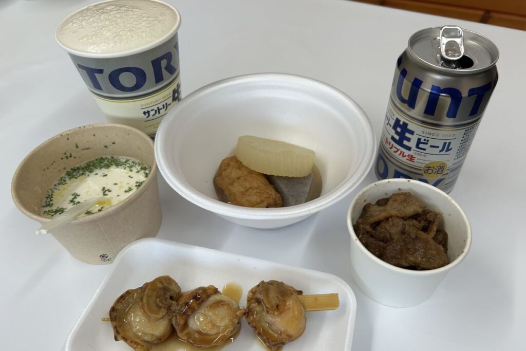 会場で提供されている、下から時計回りに、照り焼きホタテ串、ホタテミルクスープ、おでんセット、豚ジンギスカンの各種フーズ