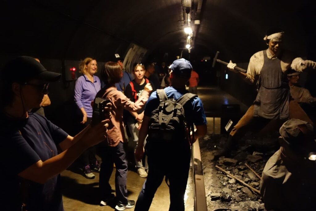 坑道を模した展示場で手堀り作業の再現を見学する参加者