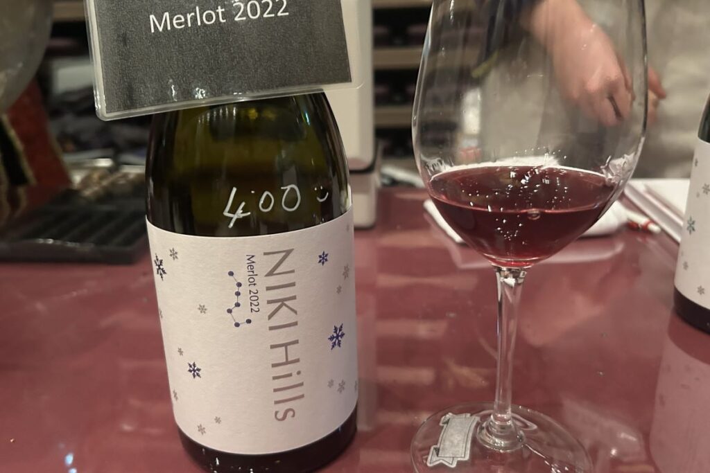 NIKI Hills wineryのメルローのボトルと注がれたグラス