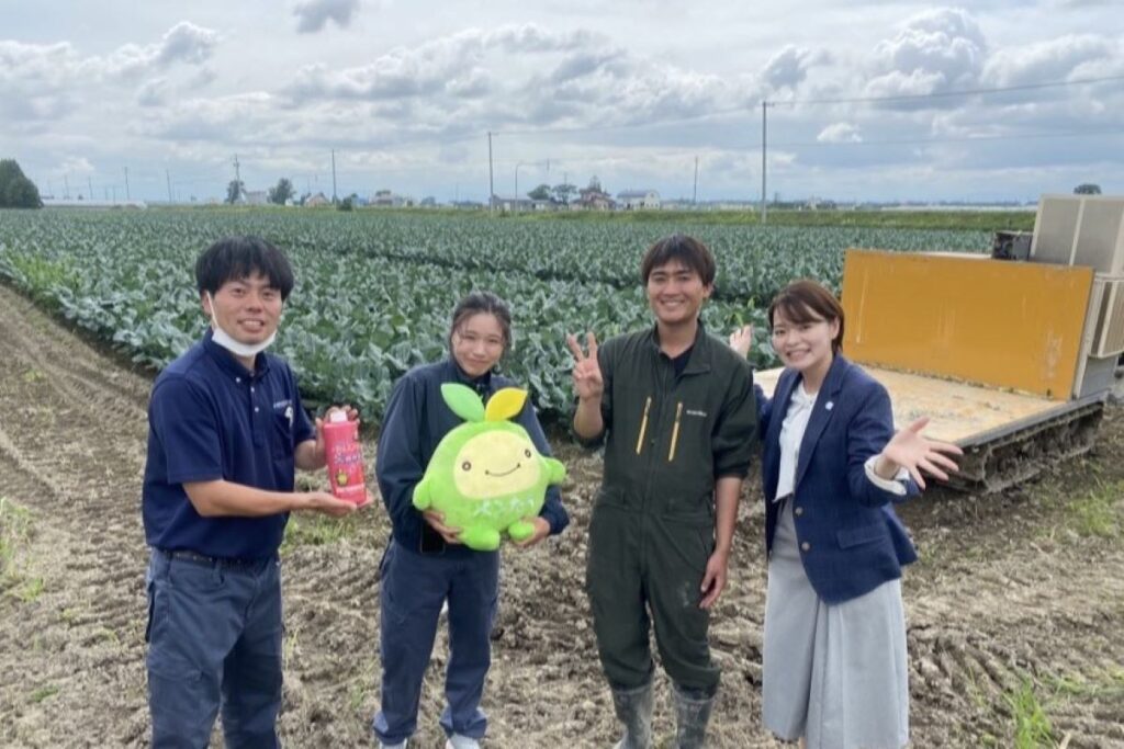 ブロッコリー畑で記念撮影する桂さん夫妻とスタッフら