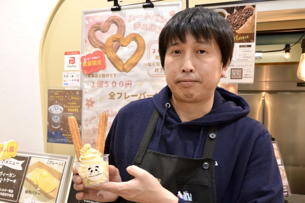 おすすめの「チュロスパフェ」を手にする、チュロパンダの遠藤さん