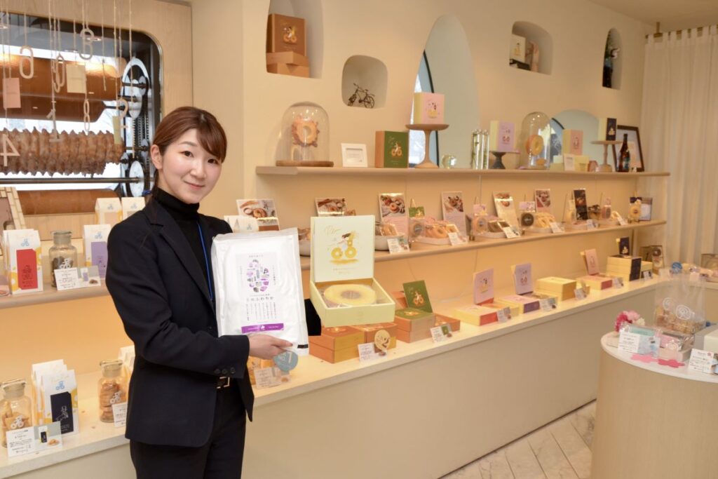 色とりどりのかわいいパッケージが並ぶ、ring ringの店内で、商品を紹介する佐々木さん。同社製造の米粉も販売しています
