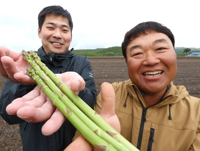 自慢のアスパラガス「ラスノーブル」を持ち、笑顔を見せるＪＡびえいの高橋巧さん（左）と白金アスパラガス生産部会の沢尻朋希さん